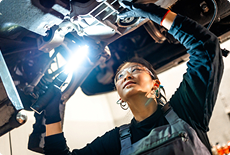 Technician inspecting a vehicle under a work light