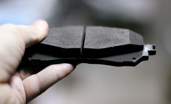 Mechanic-Holding-Brake-Pad-At-Garage Mechanic-Holding-Brake-Pad-At-Garage