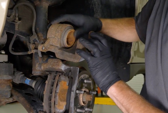 brake-system-inspection-part2-hero-step3-remove-caliper Technician removing brake caliper from brake system