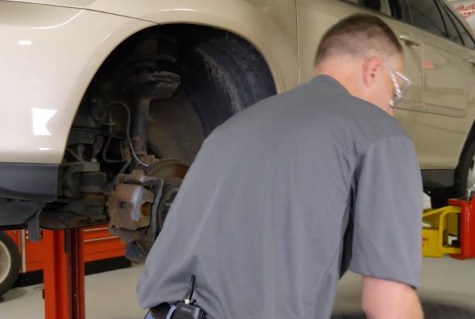 Technician putting vehicle on lift to inspect brake system