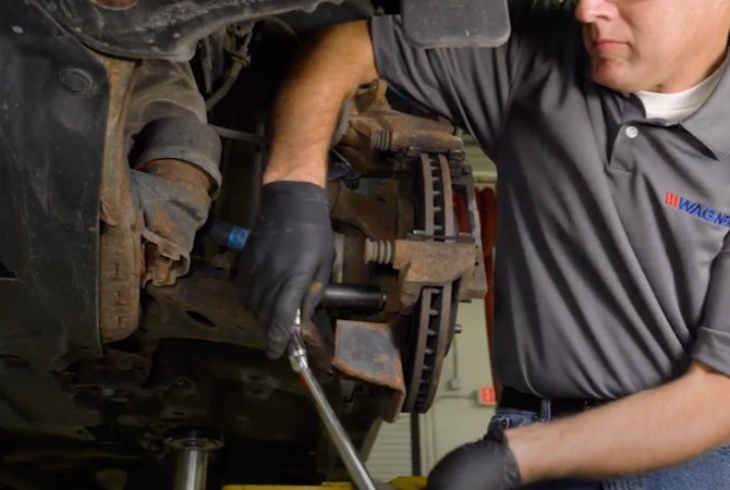 brake-system-inspection-part3-step3-brake-caliper Technician removing brake caliper from brake system