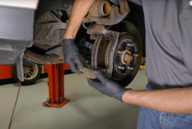 Technician looking at caliper slide pin boots on a brake system