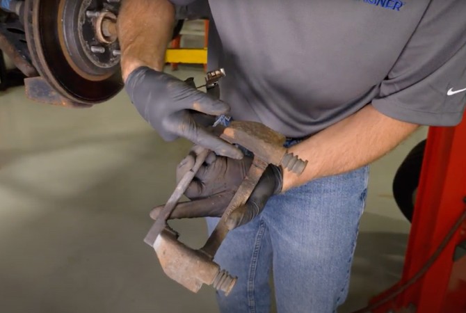 Technician examining brake caliper hardware from a brake system