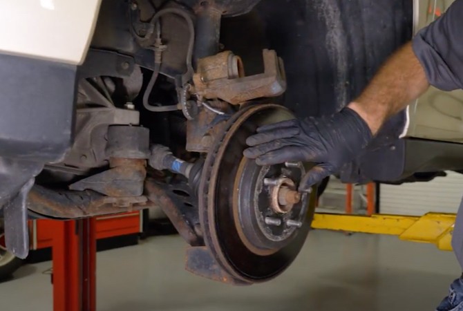 Technician examining brake rotor on brake system