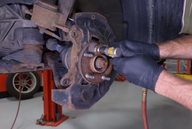 how-to-do-complete-brake-job-step-5 Technician cleaning hub with brush attachment