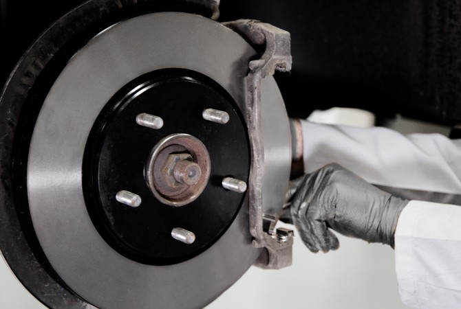 Technician installing Wagner rotors on a vehicle that has been lifted up at the shop.