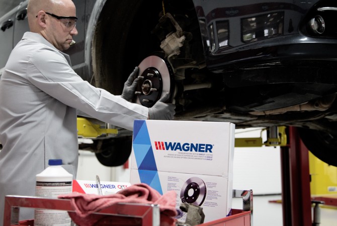 Mechanic installing Wagner brake rotors at the shop with the car lifted up.